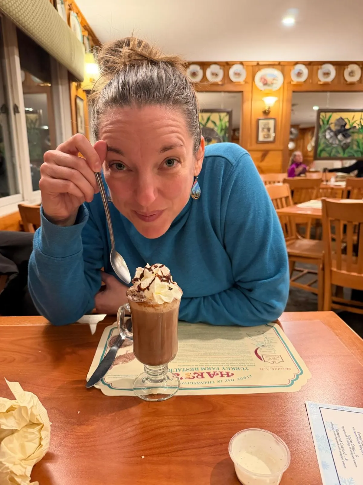 Jessica grinning, spoon raised over a whipped-cream hot chocolate