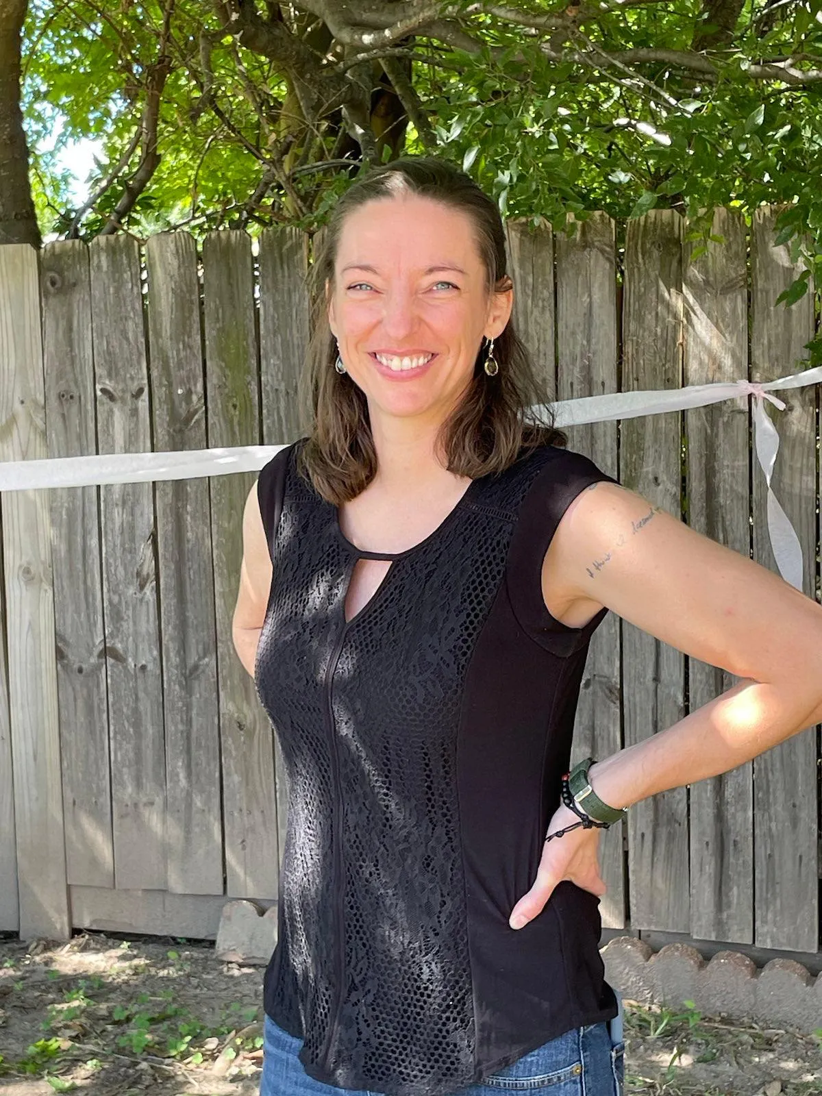 Jessica Curry smiling in dappled sunlight in front of a wooden fence